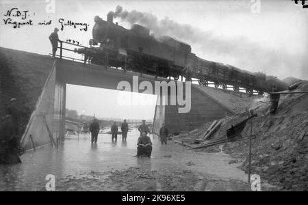 NBJ Lok 16 'Krassin', avec des trains de marchandises passe au-dessus de la nouvelle barrière routière construite à Gullspång en 1937. La locomotive a été construite par Nydqvist & Holm AB 1928 pour Nora - Bergslags Railway. Est maintenant musée sur Nora Bergslags Veteran-Jernväg. Banque D'Images