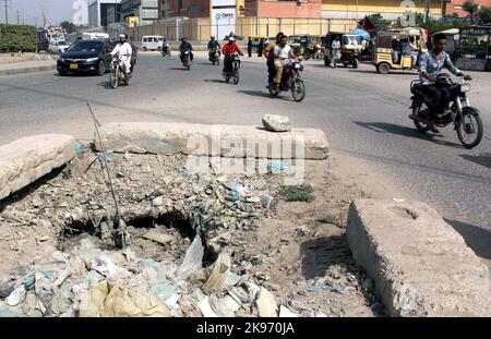 Hyderabad, Pakistan, 26 octobre 2022, les navetteurs passent par un trou principal ouvert qui peut causer tout accident grave montrant la négligence du département concerné, dans la zone industrielle de Korangi à Karachi mercredi, 26 octobre 2022. Banque D'Images