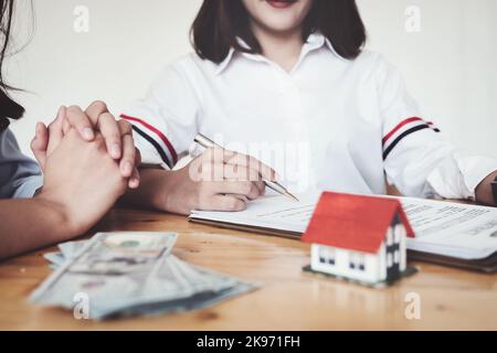 Le client tient un stylo et lit les conditions afin de signer un contrat d'achat de maison avec des documents d'assurance maison avec le vendeur. Banque D'Images
