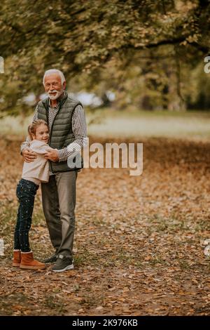 Beau grand-père passant du temps avec sa petite-fille dans le parc le jour de l'automne Banque D'Images