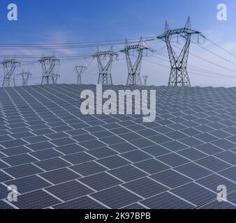 Panneaux solaires avec pylônes haute tension sur ciel bleu, usine de production d'électricité avec grande surface de panneaux solaires Banque D'Images