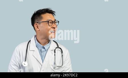 Souriant surpris Chinois d'âge moyen docteur en manteau blanc, les lunettes regarde l'espace vide Banque D'Images