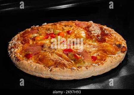 Une pizza maison brûlée sur la plaque du four électrique Banque D'Images