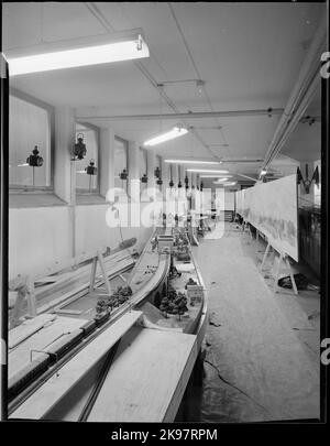 Modèle électrique de chemin de fer, en construction, représentant Stockholm Södra - Älvsjö. En arrière-plan, l'artiste G. Palmgren travaille avec l'arrière-plan de la piste modèle. Banque D'Images