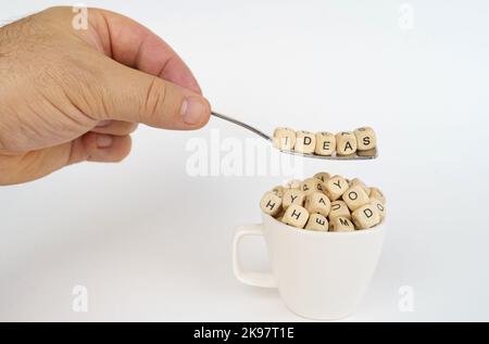 Concept d'entreprise. Les cubes avec l'image des lettres sont versés dans la tasse, au-dessus de la tasse il y a une cuillère avec des cubes avec l'inscription - idées Banque D'Images