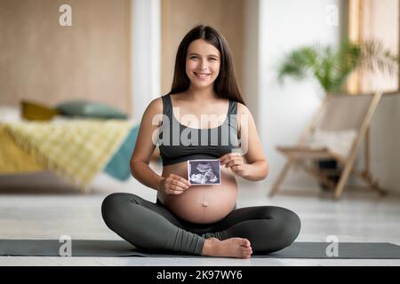 Belle jeune femme enceinte montrant sa photo d'échographie de bébé Banque D'Images