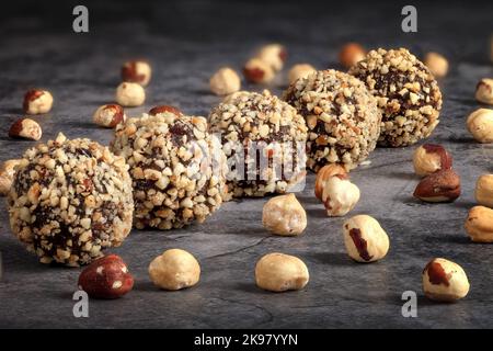 Truffes maison. Bonbons ronds. Truffe une noisette. Boules de chocolat sucrées remplies de noisettes sur fond sombre Banque D'Images