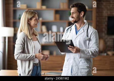 Consultation médicale. Un médecin de sexe masculin porte un uniforme parlant avec une patiente au bureau Banque D'Images