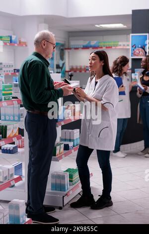 Pharmacien serviable offrant des conseils médicaux à un client âgé pendant le magasinage de médicaments en pharmacie, client âgé achetant des médicaments, suppléments, vitamine pour guérir la maladie. Support médical Banque D'Images