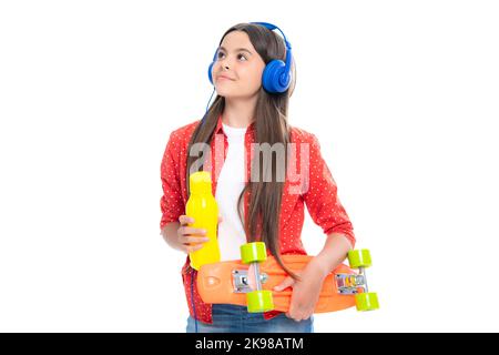 Jeune fille d'école avec bouteille d'eau de planche à roulettes et casque sur fond isolé de studio. Printemps écofille tendance, urbain style adolescent. Banque D'Images