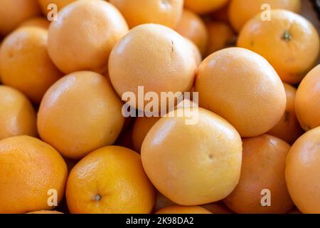 Une corbeille d'oranges de nombril bio entières fraîches empilées et à vendre sur un marché agricole. Les fruits doux et juteux colorés à l'orange avec une peau épaisse. Banque D'Images