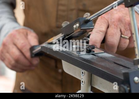 Un homme utilisant un couteau à angle fixe aiguiseur outils de cuisine sur le marché d'un agriculteur pour aiguiser des couteaux pour les clients. Le kit en acier inoxydable a un long narro Banque D'Images