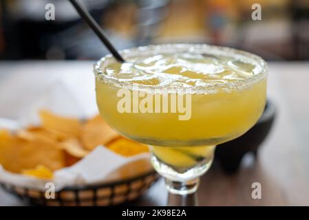 Un gros plan d'un verre de margarita de diamètre étagé rempli d'un liquide d'alcool jaune froid de tequila, glace, jus de citron, triple sec, et jus de lime. Le Banque D'Images