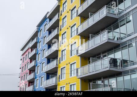 Vue sur le coin d'un grand bâtiment coloré avec parements externes rouges, bleus et jaunes. Il y a des balcons en verre à chaque étage. Banque D'Images