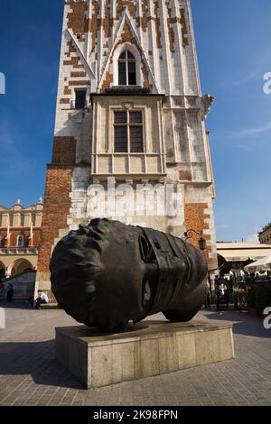 Statue de tête en bronze d'Eros Bendato et tour de l'horloge sur la place du marché principal, Cracovie, Pologne. Banque D'Images