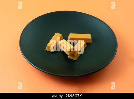 Bonbons à la barre de chocolat aux épices de citrouille sur une assiette de collation noire sur fond orange Banque D'Images