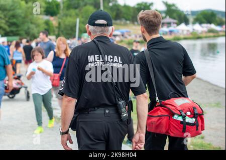 Les premiers intervenants médicaux marchent le long d'une route portant des uniformes noirs, le premier répondant médical portant des lettres grises à l'arrière du personnel paramédical. Banque D'Images