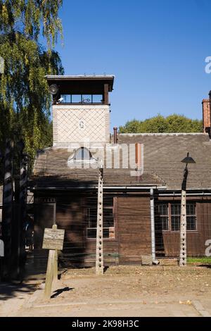 Clôture en fil barbelé et bâtiment avec tour de garde à l'intérieur de l'ancien camp de concentration nazi d'Auschwitz I, Auschwitz, Pologne. Banque D'Images