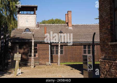 Clôture en fil barbelé et bâtiment avec tour de garde à l'intérieur de l'ancien camp de concentration nazi d'Auschwitz I, Auschwitz, Pologne. Banque D'Images