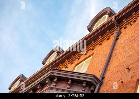 Une vue vers le haut d'un bâtiment résidentiel historique avec brique rouge, garniture en bois jaune et vert de style décoratif et fenêtres à une seule fenêtre en verre Banque D'Images