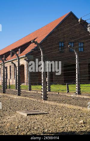 Clôtures barbelés électrifiés et bâtiment dans l'ancien camp de concentration nazi d'Auschwitz I, Auschwitz, Pologne. Banque D'Images