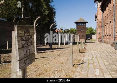 Clôtures électrifiées à barbwire et tour de garde dans l'ancien camp de concentration nazi d'Auschwitz, Auschwitz, Pologne. Banque D'Images