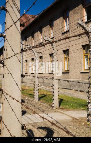 Clôtures électrifiées à barbwire et bâtiment à l'intérieur de l'ancien camp de concentration nazi d'Auschwitz I, Auschwitz, Pologne. Banque D'Images