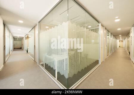 Couloir d'un étage de bureau de collègue avec des cabines séparées par des cloisons en verre Banque D'Images