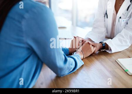 Un médecin tenant les mains d'un patient dans sa salle de consultation. Banque D'Images