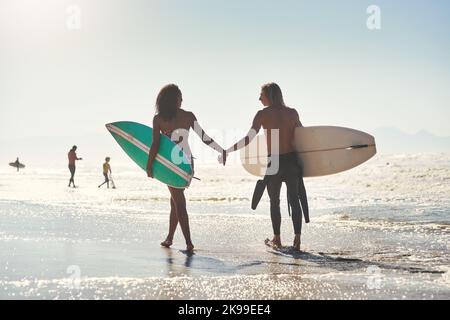 Le surf est quelque chose que vous apprécierez tous les deux. Un jeune couple passe la journée à la plage avec ses planches de surf. Banque D'Images