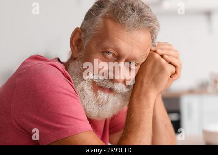 Homme barbu senior souriant dans la cuisine, en gros plan Banque D'Images