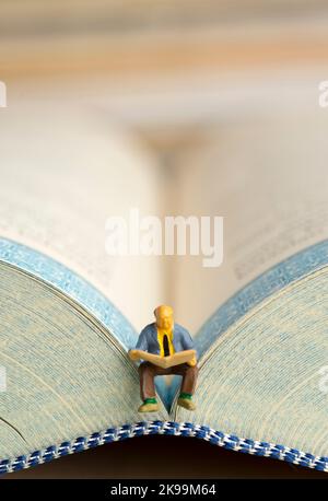 Gros plan de figurines miniatures d'un vieil homme lit le journal. Banque D'Images