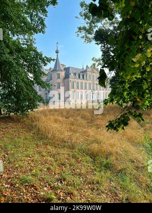 Des peintures pittoresques verticales et colorées ont été prises sur le château historique de Poeke, vu à travers les arbres verts et les feuilles Banque D'Images