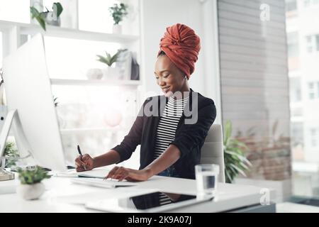 Elle écrit toutes ses idées. Une jeune femme d'affaires attirante prend des notes tout en travaillant à son bureau. Banque D'Images