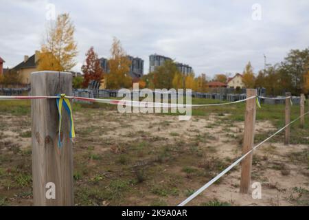 Butscha, Ukraine. 21st octobre 2022. Un petit drapeau ukrainien pend d'une clôture sur le terrain de l'église où les résidents qui sont morts pendant l'occupation russe ont été enterrés dans une fosse commune. Peu d'endroits en Ukraine sont devenus autant un symbole de la brutalité de la guerre d'agression de la Russie que Butscha. Plus d'un demi-an après le retrait des forces d'occupation, les résidents reprennent leur vie quotidienne. Pour beaucoup, cependant, la guerre est loin d'être terminée. Credit: Hannah Wagner/dpa/Alay Live News Banque D'Images