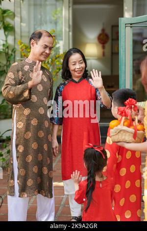 Un couple senior heureux salue leurs enfants et petits-enfants venus pour la célébration de Tet Banque D'Images