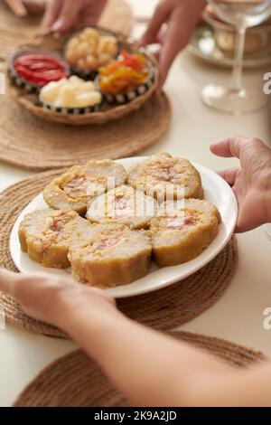 Gros plan de la femme apportant une assiette avec un gâteau de riz collant traditionnel à la table du dîner Banque D'Images