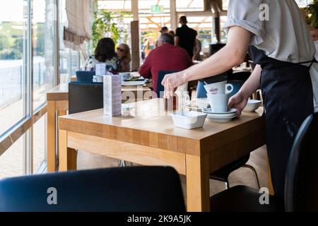 Un ouvrier de cuisine qui débarque des tables dans un restaurant animé de Newquay, en Cornouailles, au Royaume-Uni. Banque D'Images