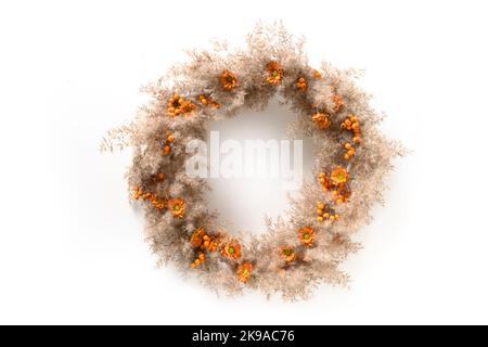 Couronne de Thanksgiving avec des fleurs orange et des matériaux naturels secs isolés sur fond blanc. Vue de dessus. Banque D'Images