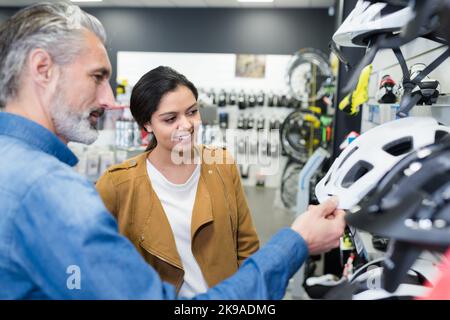 jeune femme choosesin casque dans la boutique de vélos Banque D'Images