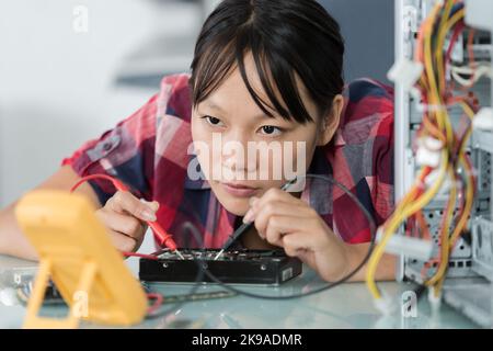 technicien utilisant un multimètre pour tester un composant du calculateur Banque D'Images