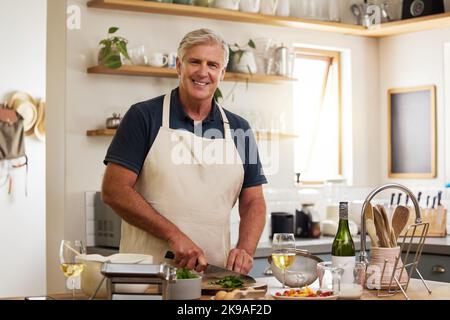 Portrait d'homme senior, cuisine dans la cuisine et préparation de la nourriture, repas de déjeuner et dîner à la maison. Un chef cuisinier mûr et heureux hache les ingrédients au couteau Banque D'Images