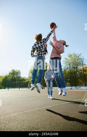 Jeunes garçons et filles, étudiants se liant à l'extérieur pour jouer au basket-ball de rue. Les adolescents portant des vêtements décontractés. Jeunesse, sport, énergie, mouvement, actif Banque D'Images