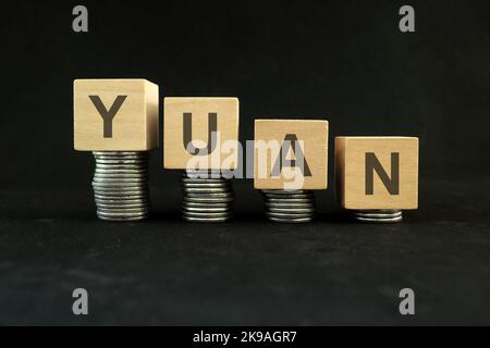 Le concept de dépréciation de la monnaie chinoise, de dépréciation de la valeur et de dévaluation. Diminution de la pile de pièces sur fond noir foncé. Banque D'Images