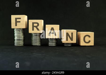 Affaiblissement de la monnaie suisse et française, dépréciation de la valeur et dévaluation concept. Diminution de la pile de pièces sur fond noir foncé. Banque D'Images