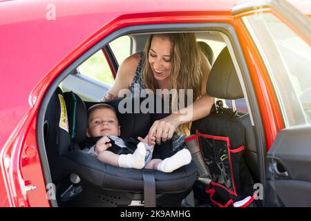 Mère fixe son fils sur le siège de voiture et met sa ceinture de sécurité Banque D'Images