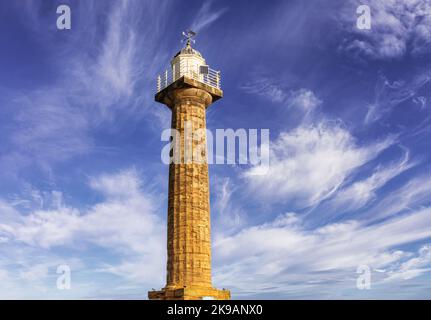 Un phare s'élève contre un ciel rempli de nuages plus sombres. Une ailette d'étanchéité est montée sur le dôme en haut. Banque D'Images