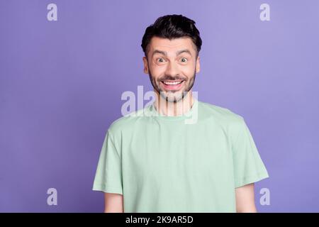 Photo de l'extatique surjoyeuse gars avec la coiffure brunet T-shirt de chaume impressionné regardant la caméra isolée sur fond violet de couleur Banque D'Images