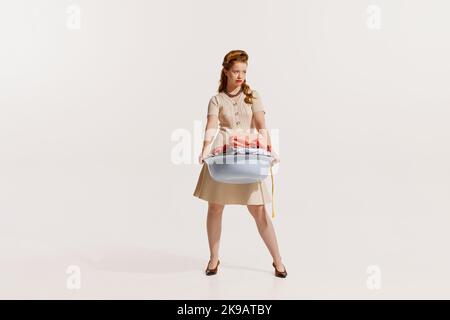 Portrait d'une jeune femme élégante se lavant, portant un bol avec des vêtements isolés sur fond blanc Banque D'Images