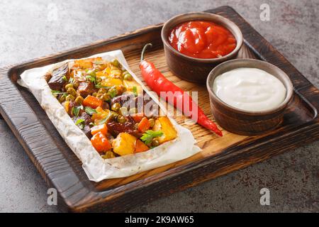 Kebab turc avec des légumes enveloppés de papier sulfurisé sur un plateau en bois sur la table. Horizontale Banque D'Images